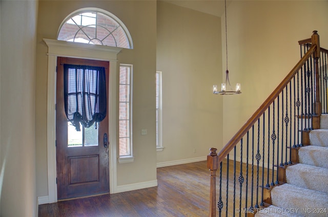 foyer featuring a towering ceiling, dark hardwood / wood-style flooring, and an inviting chandelier