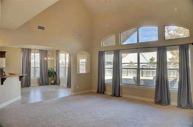 unfurnished living room with a notable chandelier, light colored carpet, and high vaulted ceiling