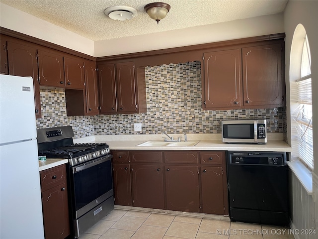 kitchen featuring light tile patterned flooring, sink, tasteful backsplash, dark brown cabinets, and appliances with stainless steel finishes