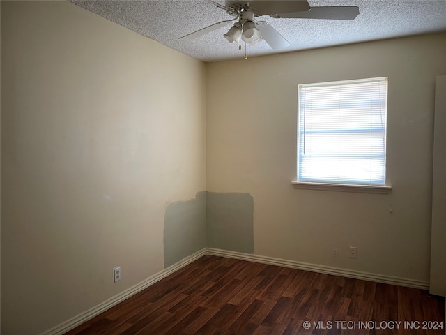 spare room with a textured ceiling, ceiling fan, dark wood-type flooring, and a wealth of natural light