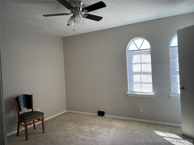 interior space with a textured ceiling, light carpet, and ceiling fan