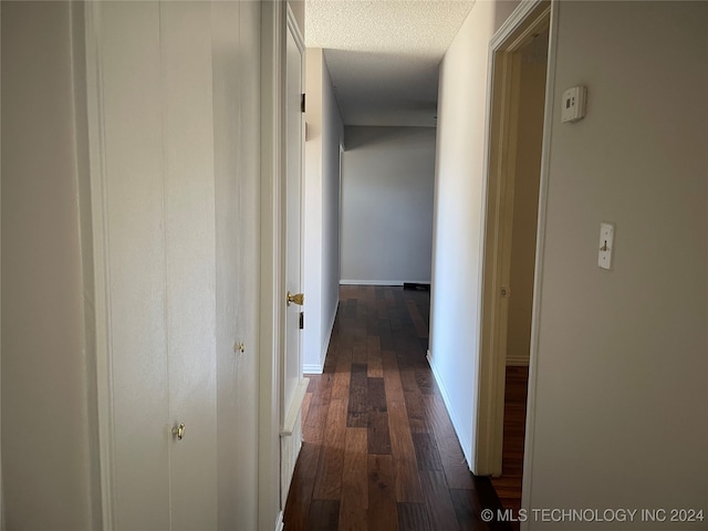 hallway with a textured ceiling and dark hardwood / wood-style floors