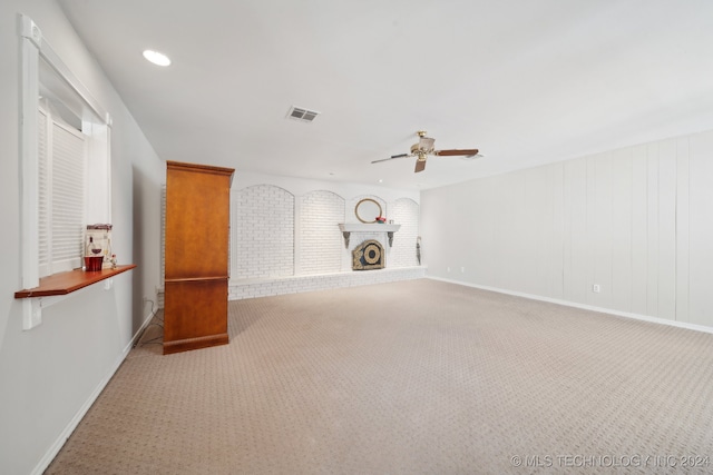 unfurnished living room featuring ceiling fan, light colored carpet, and a fireplace