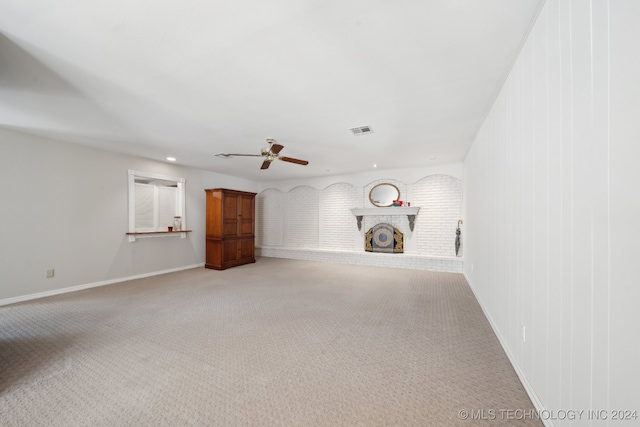 unfurnished living room featuring ceiling fan, carpet floors, and a fireplace