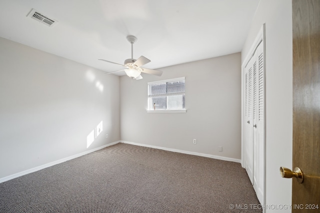 unfurnished bedroom featuring ceiling fan, a closet, and dark carpet