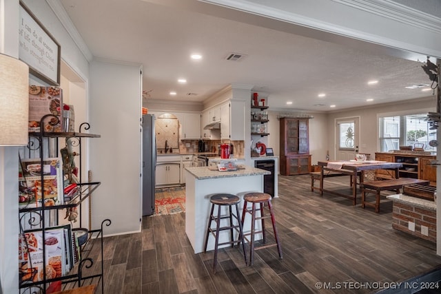 kitchen featuring white cabinetry, ornamental molding, tasteful backsplash, dark hardwood / wood-style flooring, and stainless steel fridge