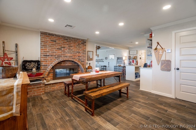 dining area with brick wall, dark hardwood / wood-style flooring, ornamental molding, and a brick fireplace