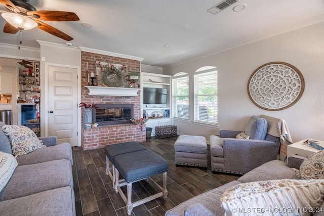 living room featuring ceiling fan, brick wall, dark hardwood / wood-style flooring, a brick fireplace, and crown molding