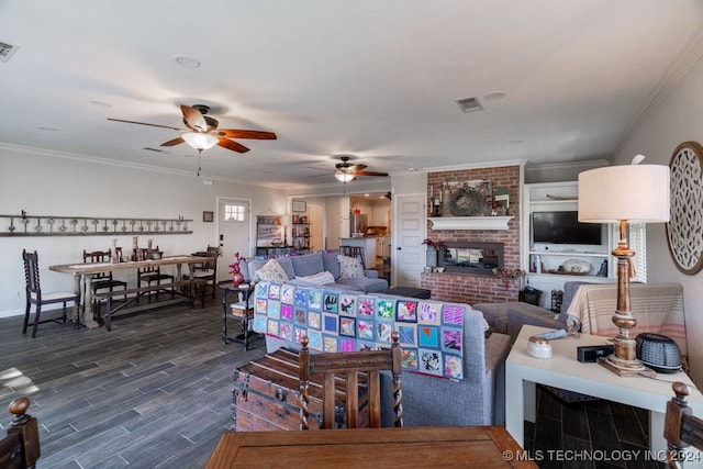 living room with ceiling fan, dark hardwood / wood-style floors, brick wall, a brick fireplace, and ornamental molding