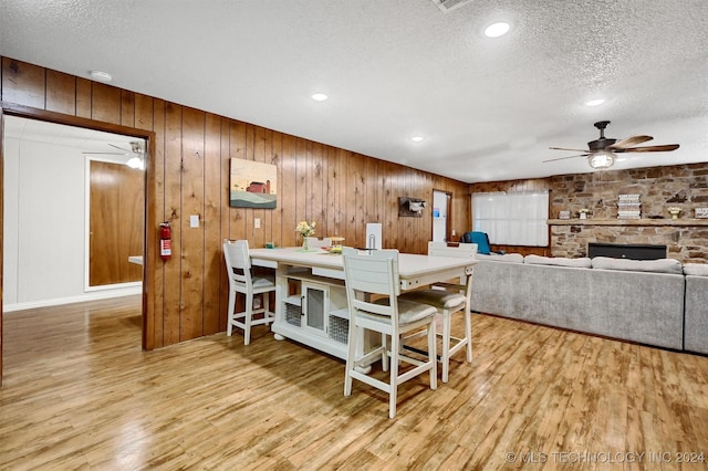 dining room featuring ceiling fan, wood finished floors, a textured ceiling, a fireplace, and recessed lighting