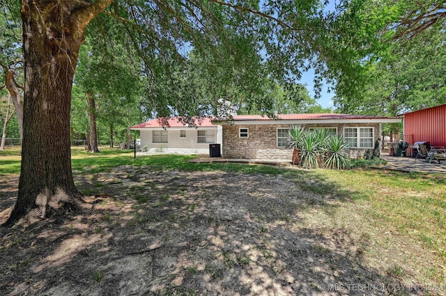 back of house featuring stone siding and a lawn