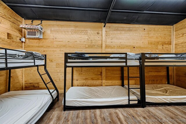 bedroom featuring wooden walls and hardwood / wood-style floors