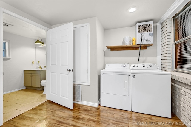 laundry room with washing machine and clothes dryer and light hardwood / wood-style flooring