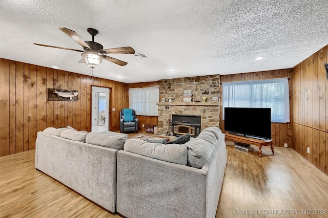 living area with a ceiling fan, visible vents, a textured ceiling, and wood finished floors