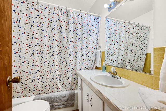 full bathroom with a textured ceiling, toilet, vanity, and shower / bath combo with shower curtain