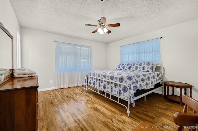 bedroom featuring a textured ceiling, ceiling fan, and wood-type flooring