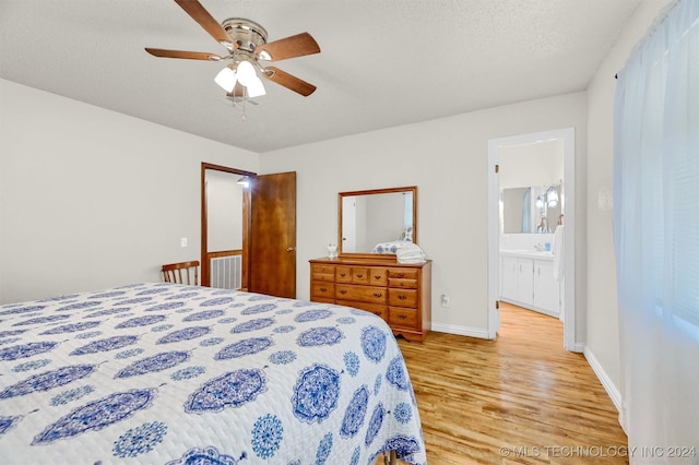 bedroom with ceiling fan, light wood-type flooring, ensuite bathroom, and a textured ceiling