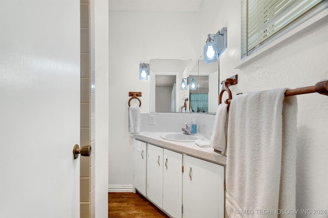 bathroom featuring decorative backsplash, wood finished floors, and vanity