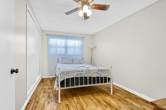 bedroom featuring a ceiling fan, baseboards, and wood finished floors