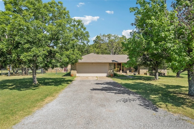 view of front of house with aphalt driveway, a garage, brick siding, fence, and a front lawn