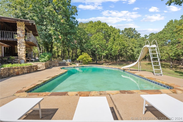 view of pool with a water slide, a patio area, and a diving board