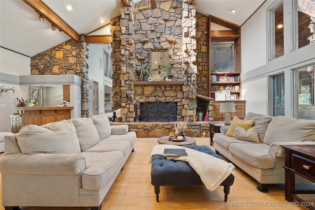 living room featuring light hardwood / wood-style floors, a stone fireplace, beam ceiling, and high vaulted ceiling