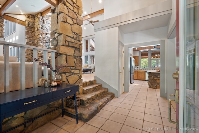 foyer featuring a high ceiling, ceiling fan, beamed ceiling, and light tile patterned flooring