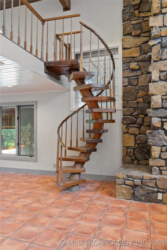 stairway featuring tile patterned flooring and beamed ceiling