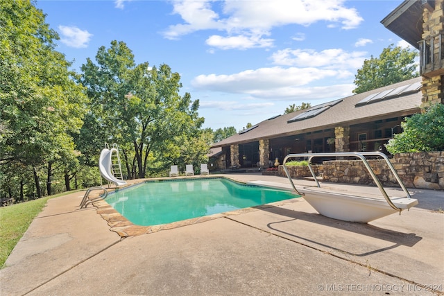 view of swimming pool featuring a patio, a water slide, and a diving board