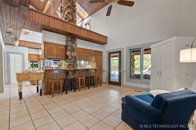 living room featuring wood ceiling, bar, high vaulted ceiling, light tile patterned floors, and ceiling fan