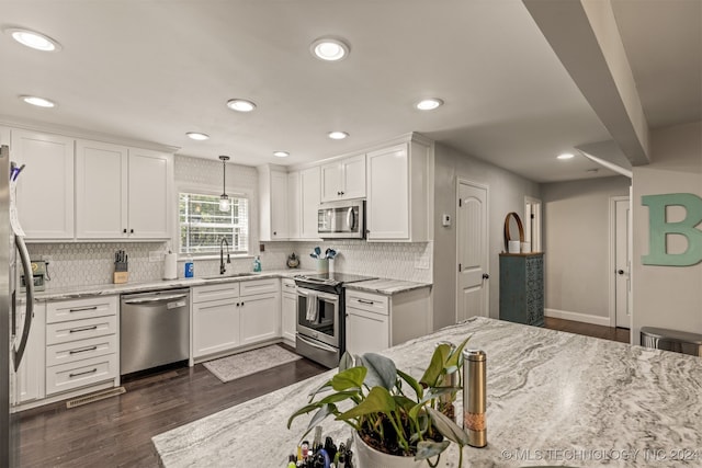 kitchen with dark wood-type flooring, pendant lighting, white cabinetry, light stone counters, and stainless steel appliances