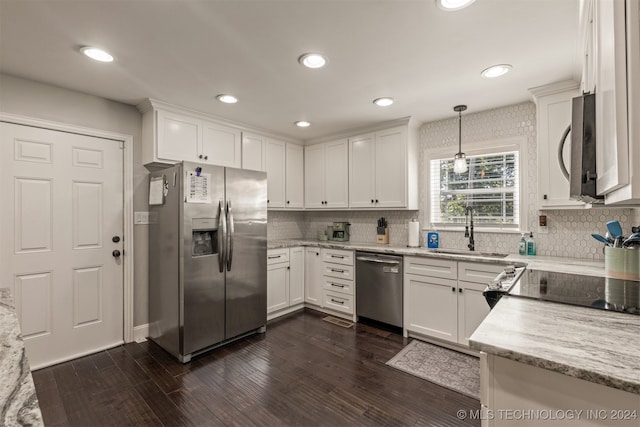 kitchen with appliances with stainless steel finishes, sink, pendant lighting, and white cabinets