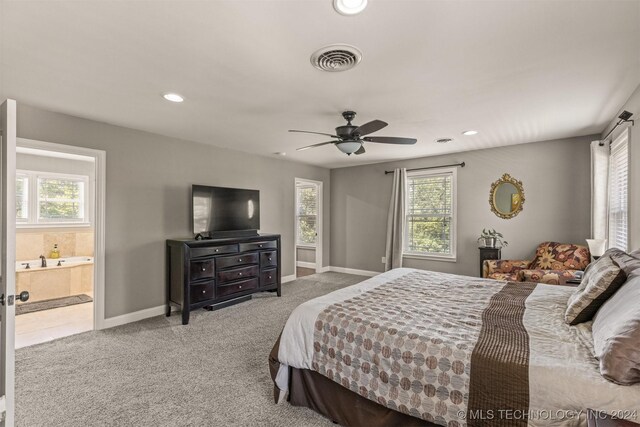 carpeted bedroom with ceiling fan, multiple windows, and ensuite bathroom