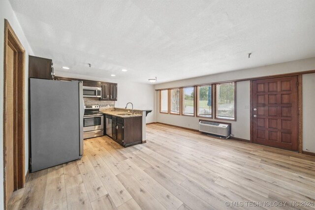 kitchen with sink, light hardwood / wood-style flooring, decorative backsplash, dark brown cabinets, and stainless steel appliances