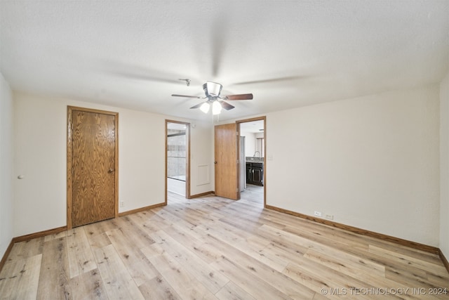 unfurnished bedroom featuring ceiling fan, ensuite bathroom, a textured ceiling, and light hardwood / wood-style floors