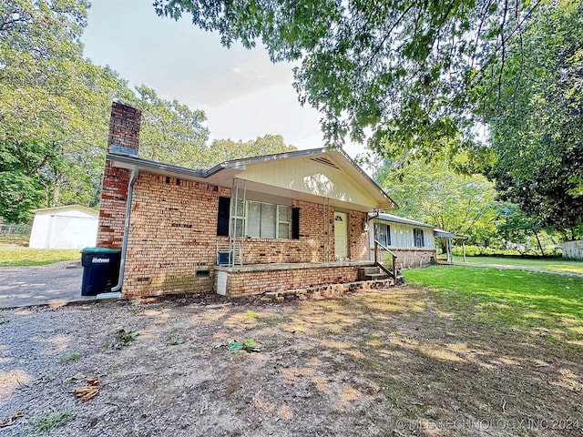 view of front of house with a porch, an outbuilding, and a front yard