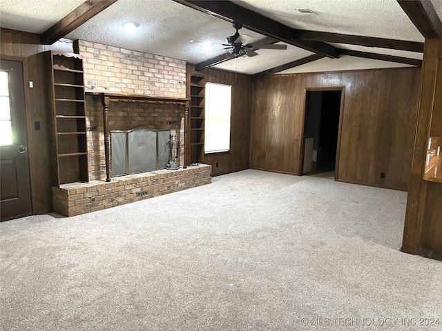 unfurnished living room with carpet, a brick fireplace, a textured ceiling, wooden walls, and ceiling fan