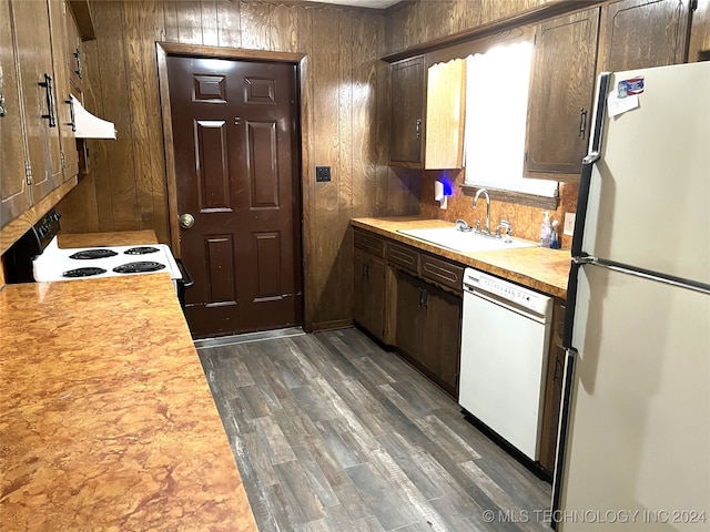 kitchen featuring sink, white appliances, wooden walls, and dark hardwood / wood-style flooring