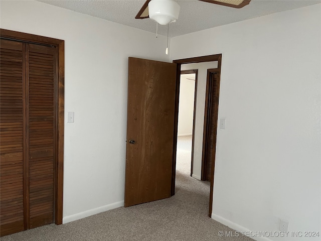 unfurnished bedroom with ceiling fan, a closet, a textured ceiling, and carpet flooring