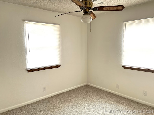 carpeted spare room featuring ceiling fan and a textured ceiling