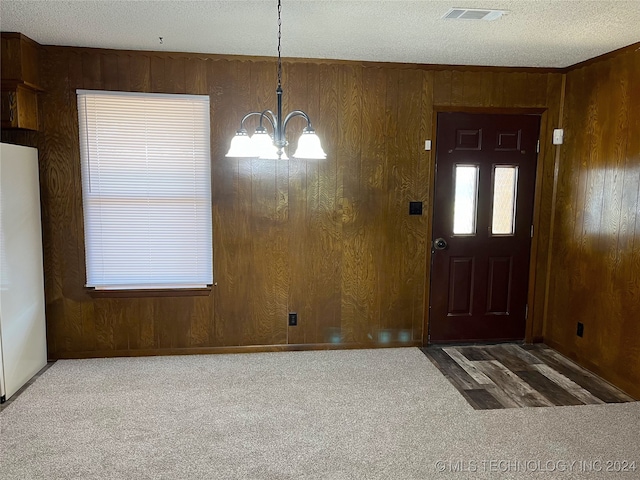 foyer entrance featuring an inviting chandelier, carpet floors, and wooden walls