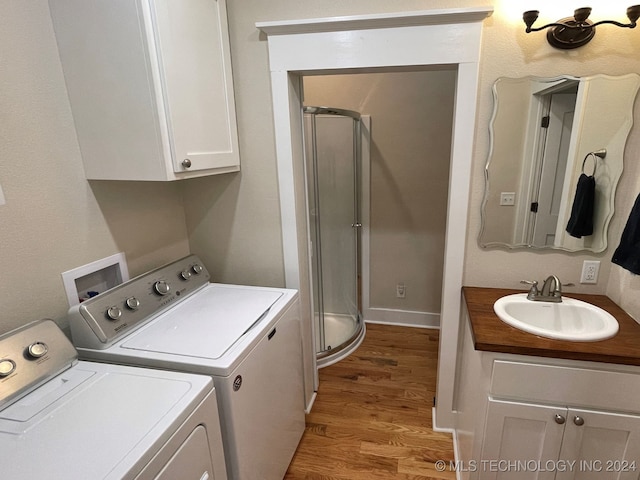 laundry room with washer and dryer, light hardwood / wood-style flooring, and sink