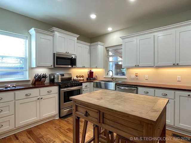 kitchen featuring white cabinets, stainless steel appliances, sink, and light hardwood / wood-style floors