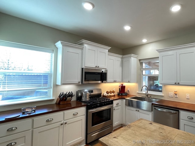 kitchen with white cabinets, appliances with stainless steel finishes, sink, and a healthy amount of sunlight