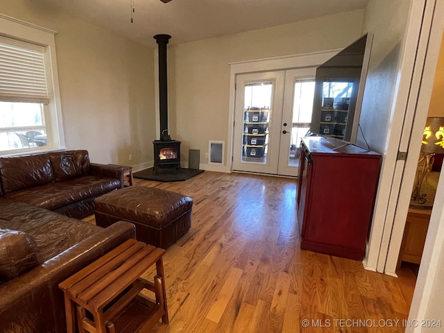 living room with hardwood / wood-style flooring, a wealth of natural light, ceiling fan, and a wood stove