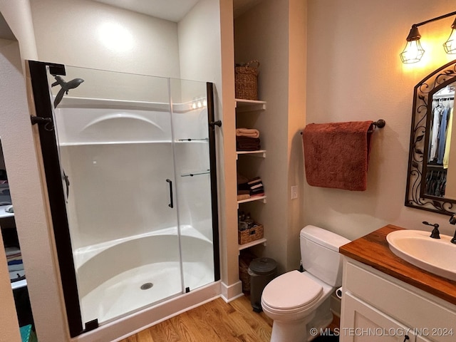 bathroom featuring a shower with door, vanity, toilet, and hardwood / wood-style flooring