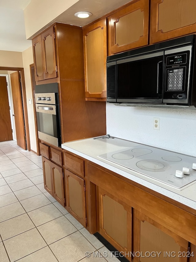 kitchen with white electric stovetop, light tile patterned floors, and oven