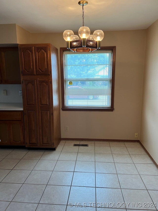 unfurnished dining area featuring light tile patterned floors and a notable chandelier