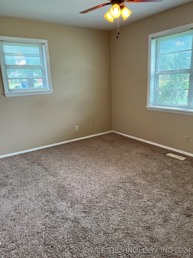 carpeted empty room with ceiling fan and a wealth of natural light