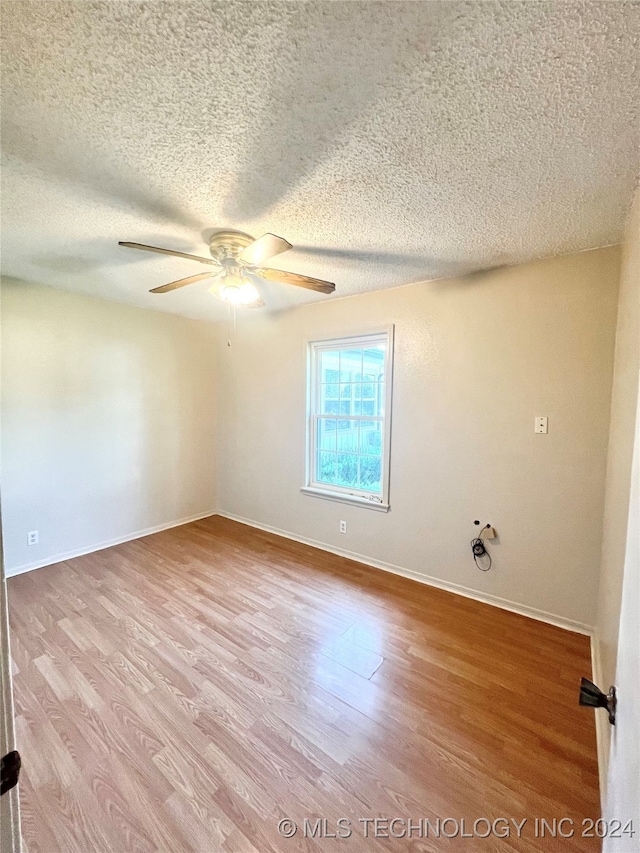 spare room with ceiling fan, a textured ceiling, and light hardwood / wood-style flooring